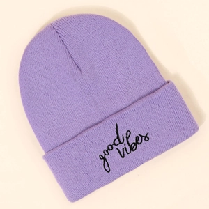 Close-up of soft purple knit beanie featuring black 'good vibes' embroidered script text