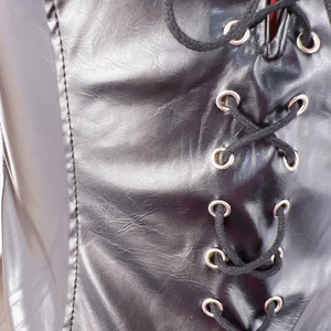 Detail of black PU jumpsuit with silver metal eyelets and black lace-up corset ties