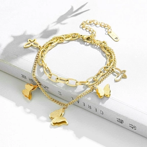 Bracelet double couche en acier titane doré avec breloques papillon sur un magazine