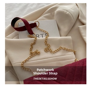 Detail of burgundy suede shoulder bag with gold chain strap and V-quilted texture