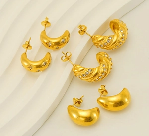 Macro shot of three pairs of gold-plated C-shaped earrings with rhinestone details