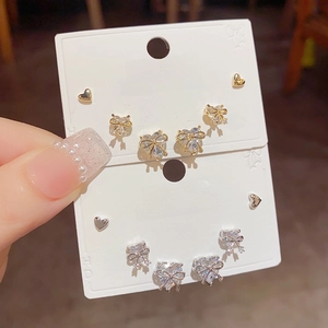 Detailed set of gold and silver stud earrings featuring heart and bow designs with zircons