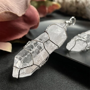 Macro view of clear quartz hexagonal point pendant wrapped in silver wire with natural ice cracks