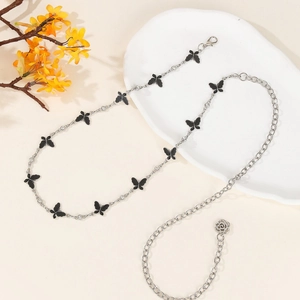 Silver butterfly waist chain with black pendants and rhinestones on a decorative white plate