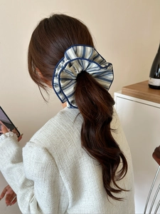 Detail of blue and white striped fabric scrunchie worn on a ponytail hair style