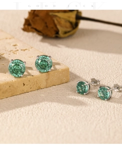Detailed close-up of emerald green round-cut studs with silver four-claw settings
