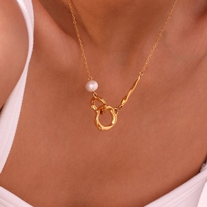 Détail du collier doré à double anneau avec une perle blanche sur un cou de femme