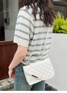 Detail of white quilted handbag featuring gold metal trim and elegant lattice pattern