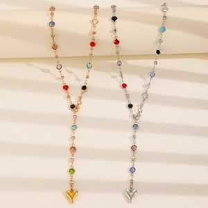 Gold and silver Y-necklaces with multicolor gemstones and heart pendants on beige paper