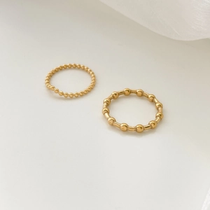 Detailed view of two gold wave-line rings with polished bead and bar textures