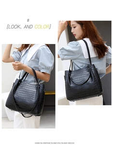 Close-up of black crocodile pattern tote bag with polished texture and metallic rivets