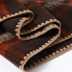Detailed close-up of dark brown and orange plaid scarf with premium blanket stitch edge