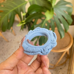 Detail shot of a blue fabric ruffle scrunchie showing elegant pleated texture