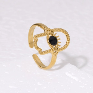 Detailed close-up of gold Hamsa Hand and Evil Eye open ring on a textured stone base