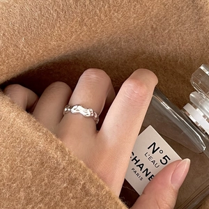 Irregular wavy silver ring showcased on hand with an elegant perfume bottle background