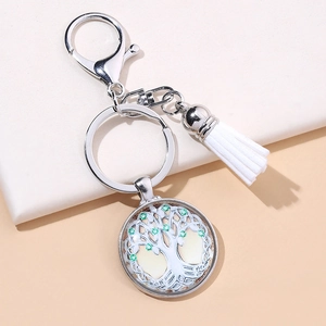 Silver Tree of Life keychain with green gems and a white tassel on a clean background