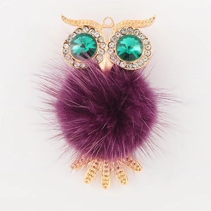 Détail de hibou avec fourrure violette, yeux en cristal vert et base en alliage doré