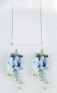 Detail of ice blue and navy bridal shoulder corsage set on white marble background