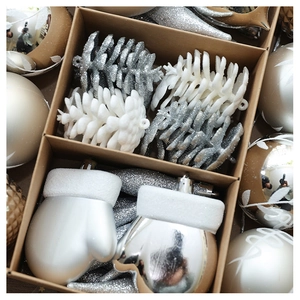 Detail of silver Christmas ornaments including pine cones and gloves in a box