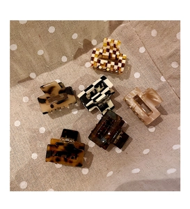 Close-up of six assorted mini acetate hair claws in leopard and checkerboard patterns