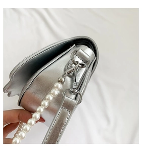 Makro-Detail der silbernen Metallic-Tasche mit Perlengriff und silbernem Schulterriemen
