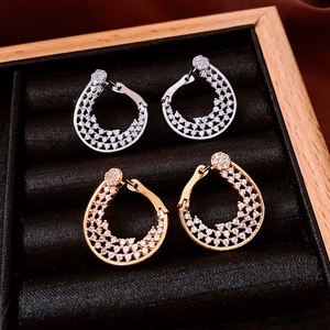 Macro view of gold and silver hoop earrings with clear zircon stones in a jewelry box