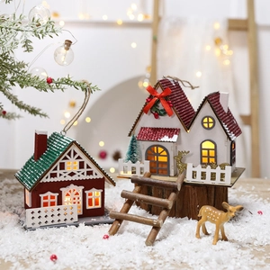 Lighted wooden Christmas house hanging ornaments with warm LED glow on snowy scene