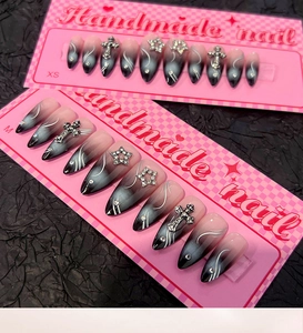 Détail de faux ongles dégradés noir et rose avec lignes argentées et croix strass