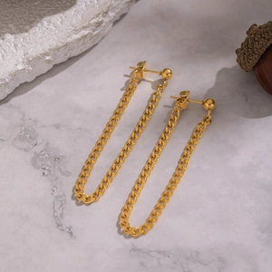 Boucles d'oreilles pendantes chaîne dorée sur marbre blanc avec accessoires déco