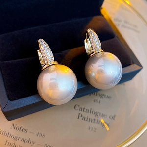 Close-up of elegant champagne pearl earrings with zircon inlay on velvet display