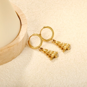 Detail of golden Christmas tree hoop earrings on elegant textured beige surface