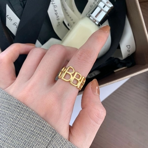 Polished gold hollow letter B stackable ring for women in a luxury unboxing scene