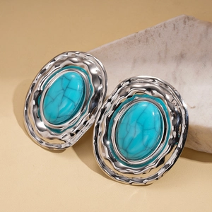 Detailed macro of silver-tone hammered metal earrings with oval turquoise resin inlay