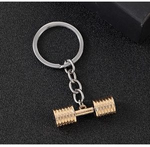 Macro view of golden dumbbell pendant with silver keyring on black textured background