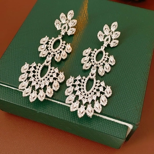 Vue détaillée des boucles d'oreilles fleur en zircon sur un écrin à bijoux vert