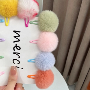 Set of colorful faux fur pom-pom hair clips in various pastel colors on a merci card