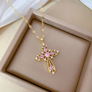 Close-up of gold cross and butterfly pendant with pink crystals in a jewelry box