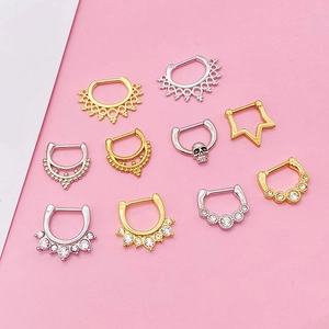 Various stainless steel septum nose rings in gold and silver on a pink background