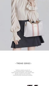 Detail of vintage white handbag with HQ print and gold metal handles held by a model