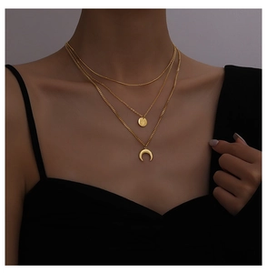 Close-up of layered gold necklace featuring celestial crescent moon and starburst charms