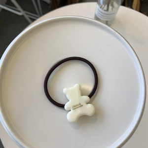 Élastique à cheveux marron avec un joli pendentif ours en résine crème sur plateau blanc