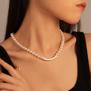 Close-up of minimalist pearl necklace featuring a matte silver curved tube on a female model