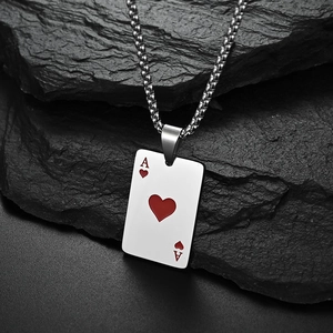 Macro shot of silver titanium Ace of Hearts poker pendant on a dark textured rock surface