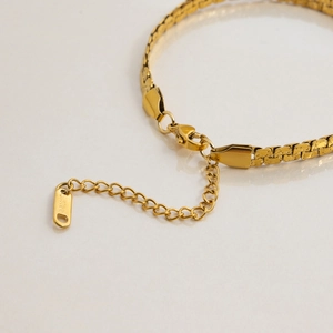 Macro detail of gold stainless steel chain showing texture and secure clasp closure