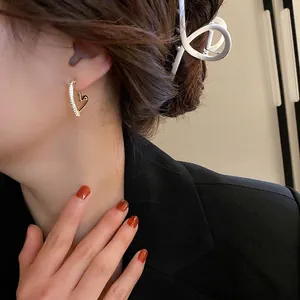 Boucles d'oreilles cœur dorées avec micro-pavage de zircons portées par un mannequin femme