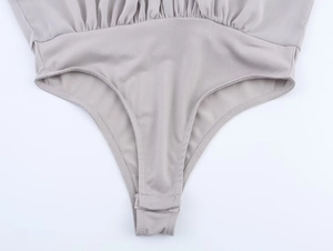 Detailed view of gray bodysuit crotch area with secure snap button closure and knit texture