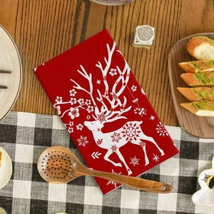 Festive red microfiber Christmas towel with white deer pattern on a checkered tablecloth