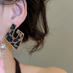 Detail of leopard print diamond earrings with gold trim on a model's ear