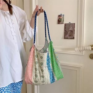 Detail of a floral patchwork tote bag with colorful fabric and blue woven rope handles