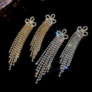 Detailed view of long tassel bow earrings in gold and silver with sparkling rhinestones